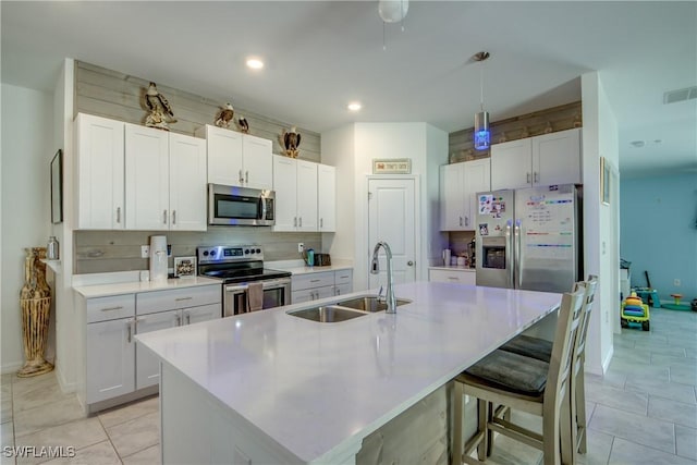 kitchen featuring an island with sink, stainless steel appliances, a sink, and light countertops