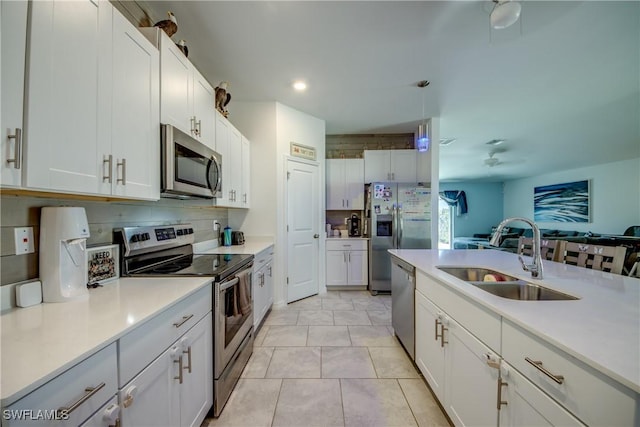 kitchen with light countertops, appliances with stainless steel finishes, a sink, and white cabinetry