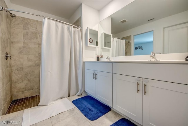 bathroom with double vanity, a shower stall, visible vents, and a sink