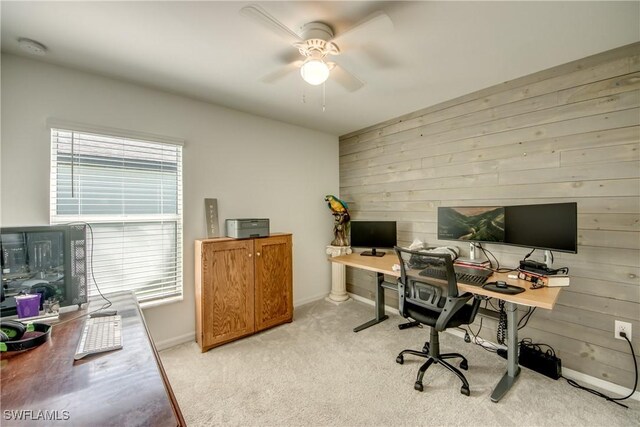 carpeted office with plenty of natural light, ceiling fan, and wooden walls