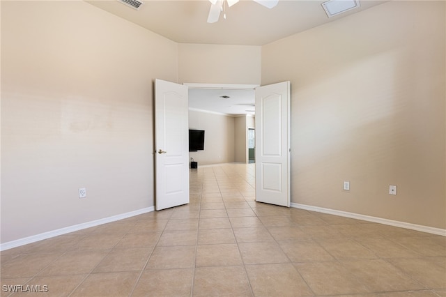 tiled spare room with ceiling fan and a towering ceiling