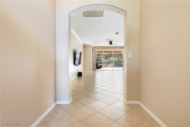 hallway featuring light tile patterned floors and ornamental molding