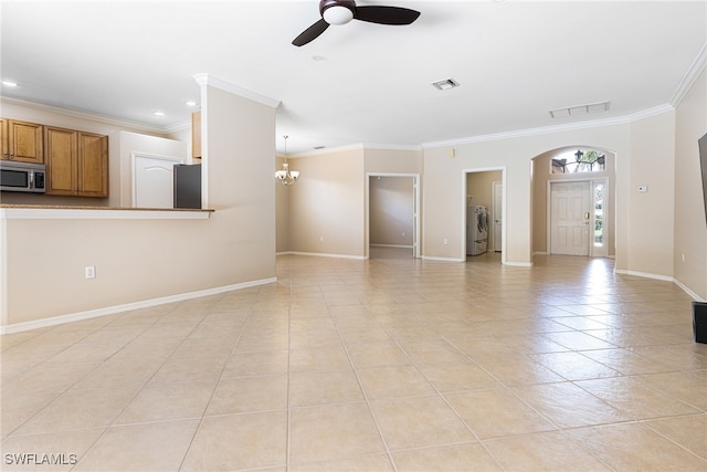 unfurnished living room featuring crown molding, washing machine and clothes dryer, ceiling fan with notable chandelier, and light tile patterned floors