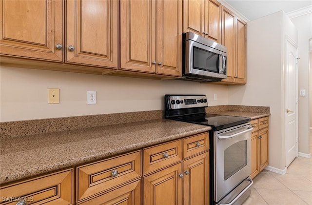 kitchen featuring light tile patterned flooring, appliances with stainless steel finishes, stone counters, and crown molding