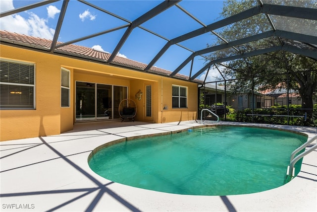 view of swimming pool featuring glass enclosure and a patio