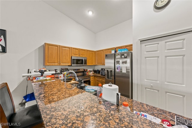 kitchen with dark stone counters, a breakfast bar area, high vaulted ceiling, kitchen peninsula, and stainless steel appliances