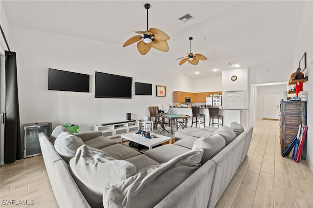 living room with ceiling fan, wine cooler, high vaulted ceiling, and light hardwood / wood-style flooring