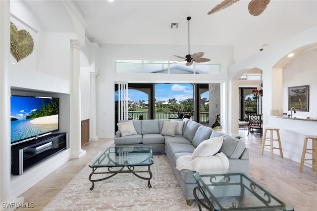 living room featuring decorative columns, a high ceiling, light tile patterned floors, and ceiling fan