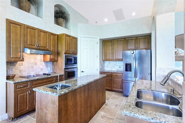 kitchen featuring appliances with stainless steel finishes, sink, a kitchen island with sink, and light stone counters