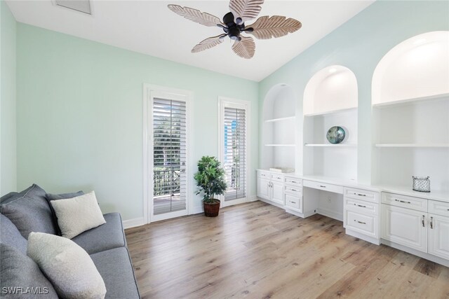 office area featuring built in desk, vaulted ceiling, built in features, light hardwood / wood-style floors, and ceiling fan