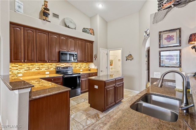 kitchen featuring appliances with stainless steel finishes, high vaulted ceiling, kitchen peninsula, a kitchen island, and sink