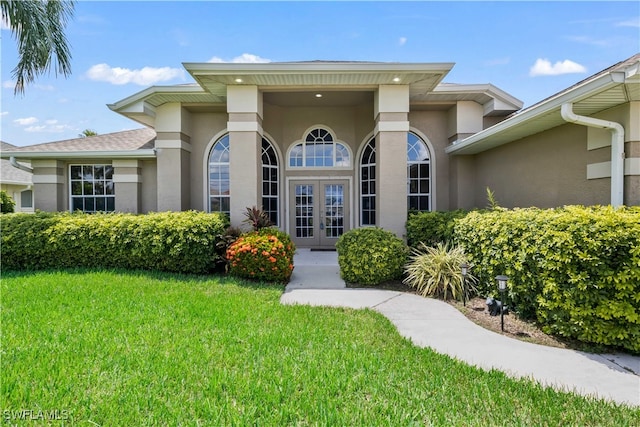 doorway to property featuring french doors and a lawn