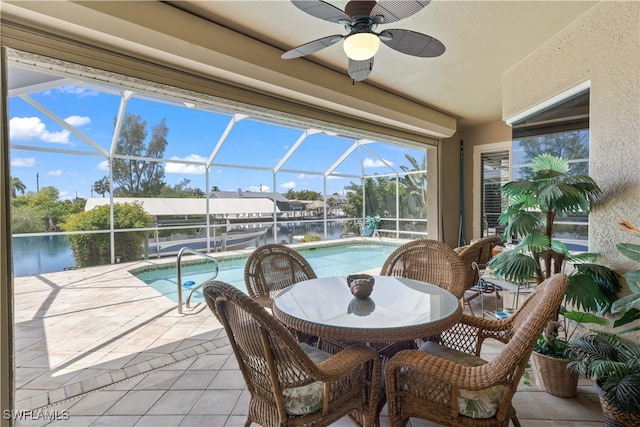 view of swimming pool featuring glass enclosure, a water view, ceiling fan, and a patio area