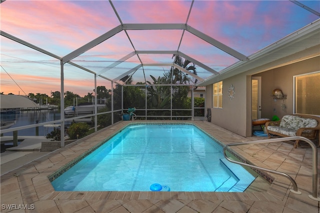 pool at dusk with a lanai and a patio area