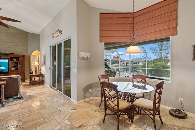 dining area with a water view, lofted ceiling, and ceiling fan