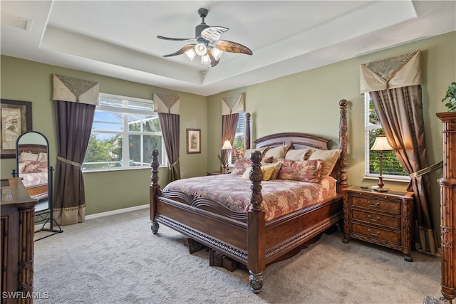 carpeted bedroom featuring a tray ceiling and ceiling fan