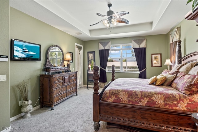 carpeted bedroom featuring ceiling fan, a raised ceiling, and multiple windows