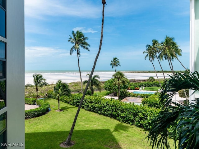 view of community featuring a water view, a yard, and a view of the beach