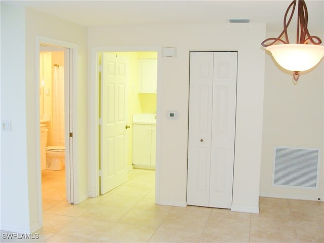 unfurnished bedroom featuring light tile patterned floors and ensuite bath