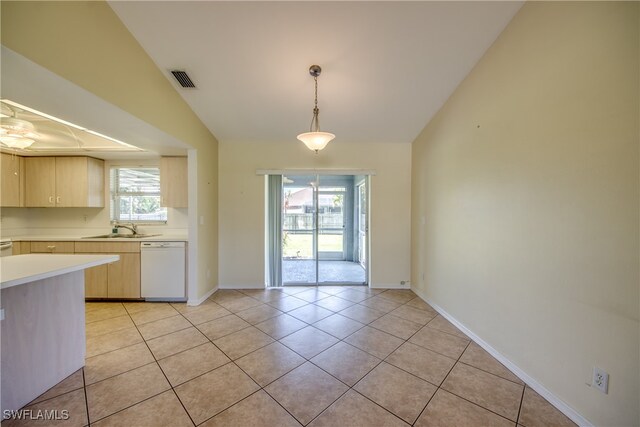 kitchen featuring light tile patterned flooring, lofted ceiling, light brown cabinetry, white dishwasher, and sink