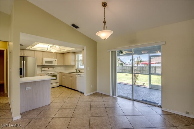 kitchen with white appliances, light tile patterned floors, vaulted ceiling, sink, and decorative light fixtures