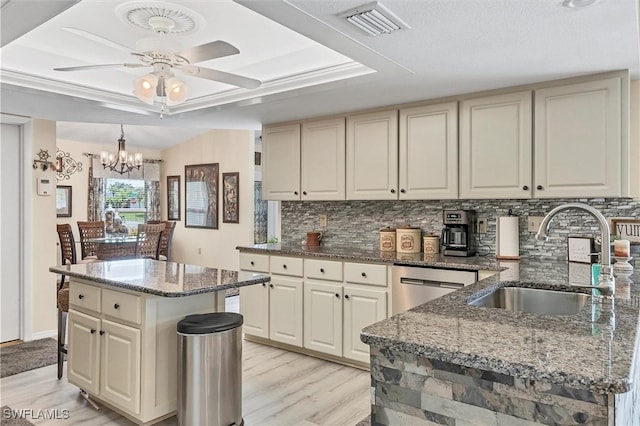 kitchen featuring light hardwood / wood-style floors, decorative backsplash, sink, a center island, and dark stone countertops