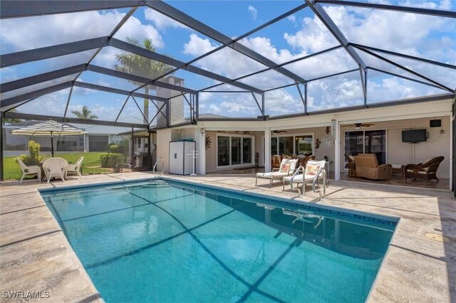 view of pool featuring glass enclosure, a patio, and ceiling fan