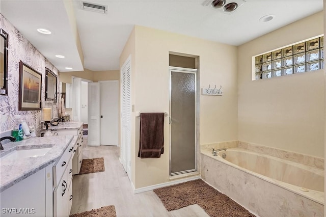 bathroom featuring wood-type flooring, shower with separate bathtub, and dual bowl vanity