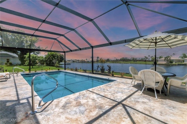 pool at dusk featuring glass enclosure, a patio, and a water view