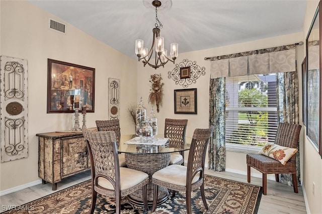 dining area with light hardwood / wood-style floors and a notable chandelier