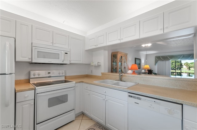 kitchen with light tile patterned floors, sink, white appliances, and white cabinets