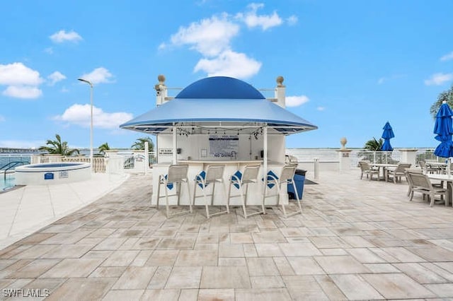 view of patio / terrace featuring a water view, an outdoor bar, and a gazebo