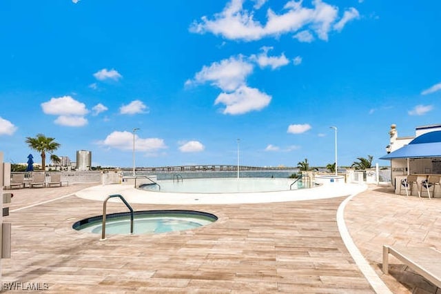 view of swimming pool featuring a hot tub and a patio area