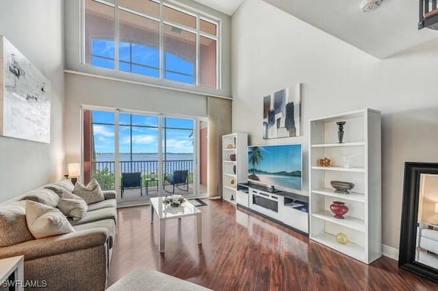 living room with hardwood / wood-style flooring, built in features, and a towering ceiling