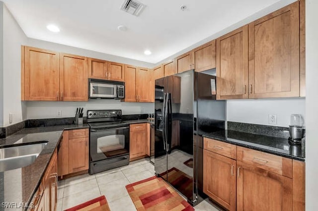 kitchen with light tile patterned floors, black appliances, and dark stone countertops