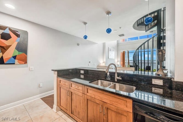 kitchen with black dishwasher, sink, dark stone countertops, decorative light fixtures, and light tile patterned floors