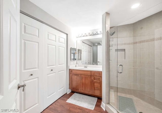 bathroom featuring wood-type flooring, a shower with door, and vanity