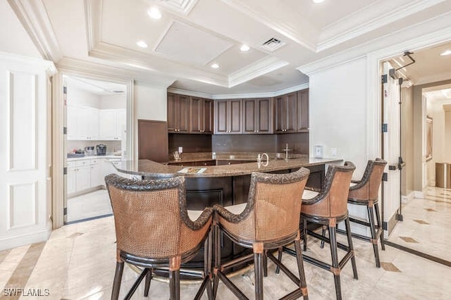 kitchen featuring white cabinetry, a kitchen breakfast bar, decorative backsplash, ornamental molding, and dark brown cabinets