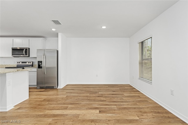 kitchen with light stone counters, light wood finished floors, visible vents, appliances with stainless steel finishes, and white cabinets