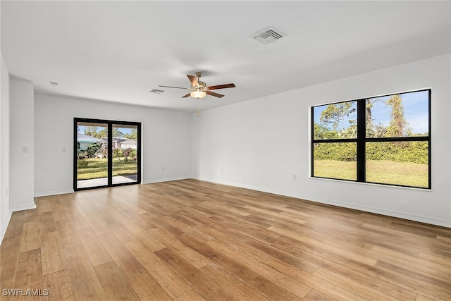 spare room featuring light wood-style flooring, a ceiling fan, visible vents, and baseboards