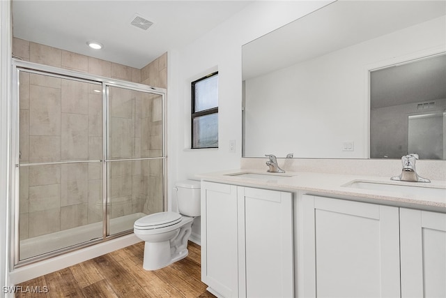 bathroom with an enclosed shower, hardwood / wood-style flooring, dual vanity, and toilet