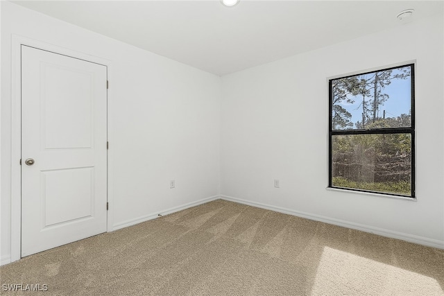 carpeted empty room featuring baseboards