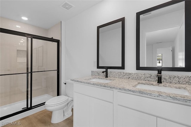 full bath with toilet, a shower stall, wood finished floors, double vanity, and recessed lighting