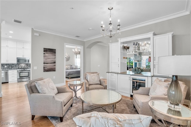 living room with an inviting chandelier, light hardwood / wood-style flooring, and crown molding