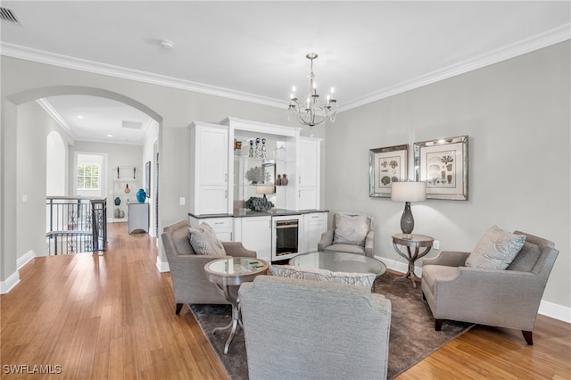 living room with wine cooler, a chandelier, light hardwood / wood-style flooring, and ornamental molding