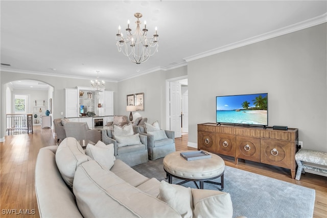 living room with wine cooler, crown molding, light hardwood / wood-style flooring, and an inviting chandelier