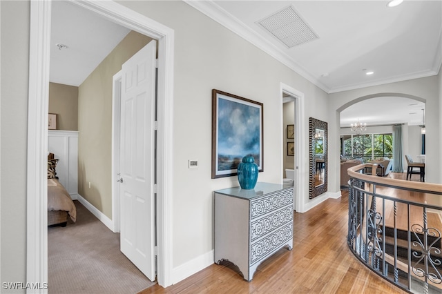 hall featuring light carpet, an inviting chandelier, and ornamental molding