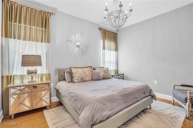 bedroom with light hardwood / wood-style flooring and an inviting chandelier