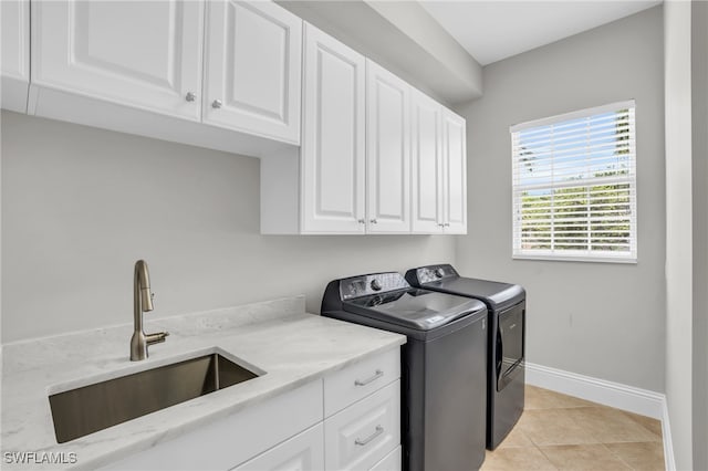 washroom featuring light tile patterned flooring, sink, washing machine and dryer, and cabinets