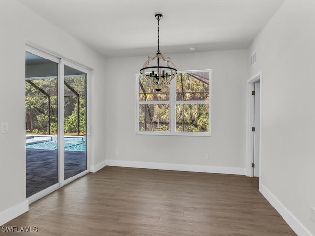 unfurnished dining area featuring dark wood-type flooring and a notable chandelier